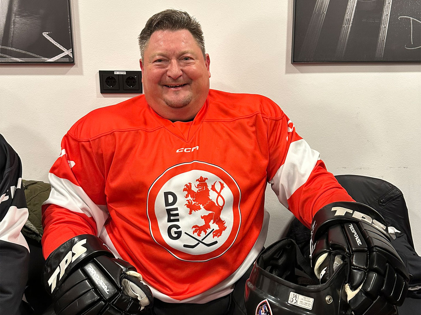 Eine Person in Eishockeytorwartausrüstung sitzt in einer Umkleidekabine.