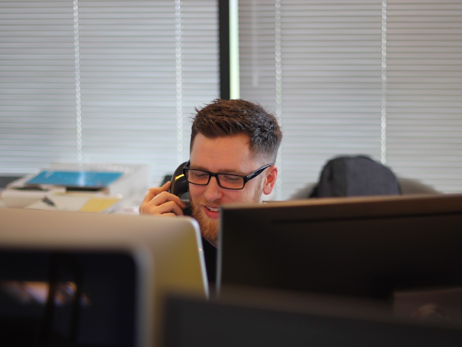 Personne au bureau avec des moniteurs d'ordinateur, visage flou, parlant au téléphone.