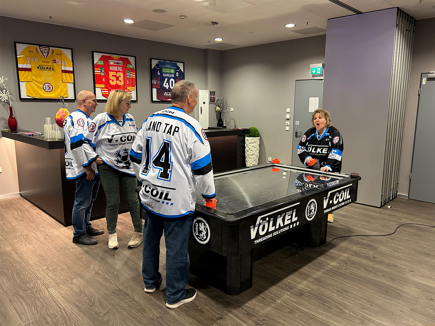 2 Teilnehmer des Hockey Days spielen Airhockey während 2 andere zuschauen