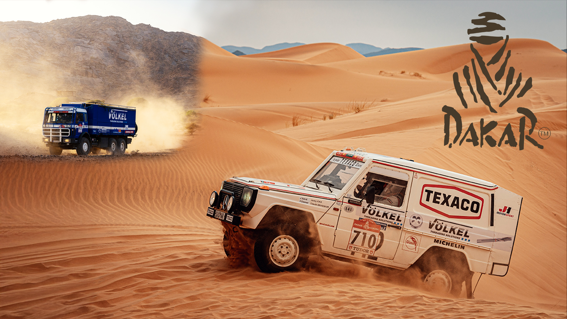 VÖLKEL-Truck und Rallye-Geländewagen meistern sandige Dünenlandschaft bei der bekannten Dakar-Wüstenrallye.