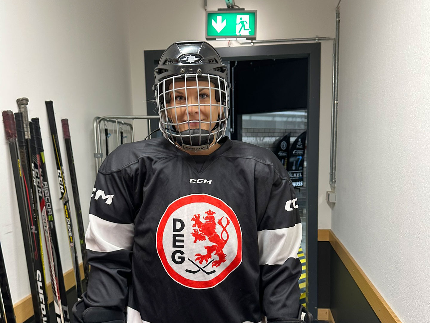 Eine Teilnehmerin des Hockey Days in schwarzer Eishockeyausrüstung steht in ein Flur.