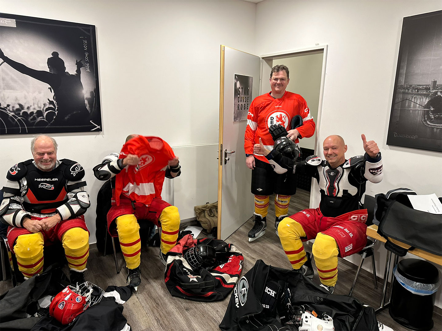 Vier Personen in Eishockeyausrüstung bereiten sich in einer Umkleidekabine auf dem Hockey Day vor