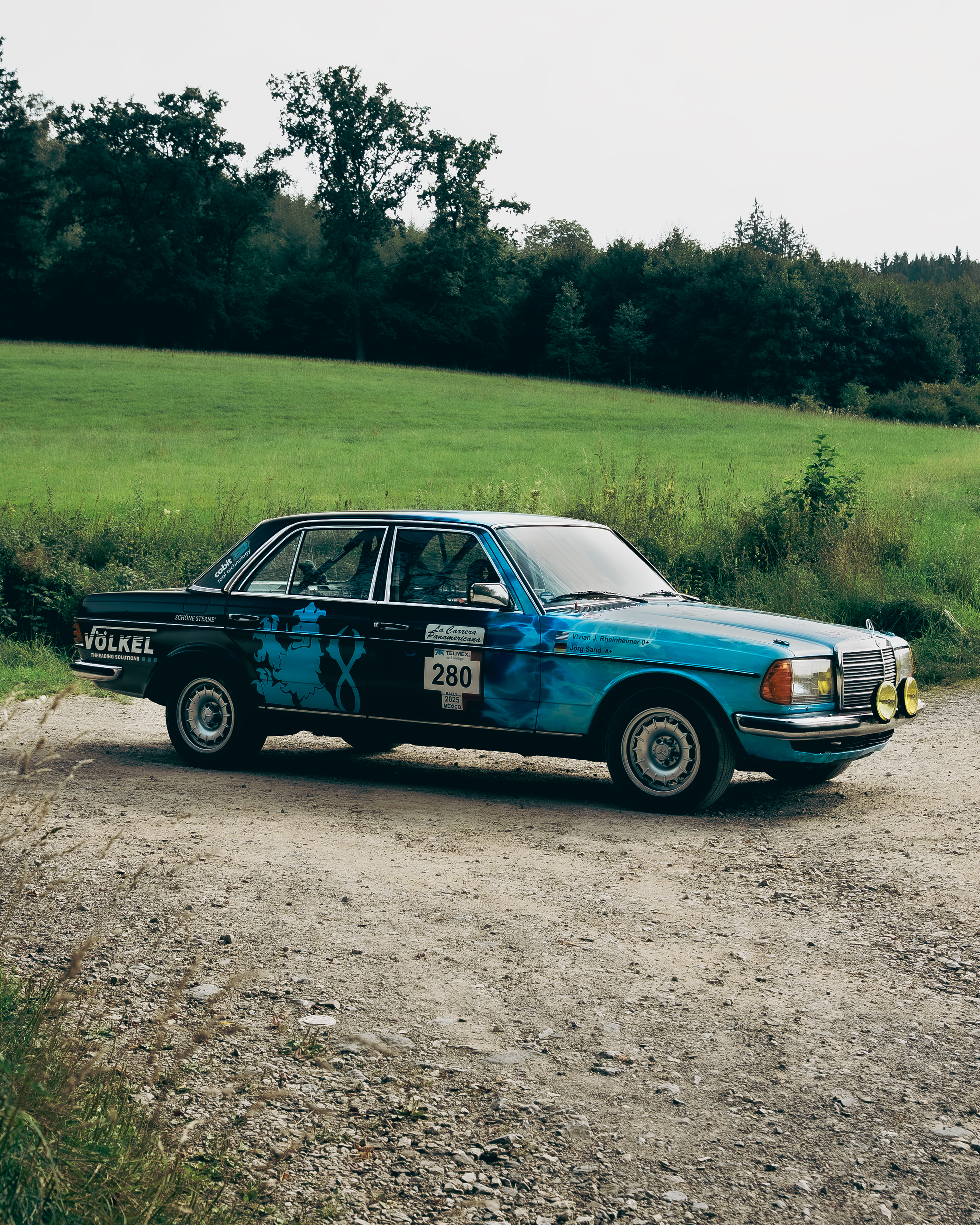 Mercedes-Benz 280E W123 Seitenansicht Rallye Seitenansicht des Mercedes-Benz 280E W123 mit blauer Rallye-Lackierung, Startnummer 280 und VÖLKEL Sponsorenlogo.