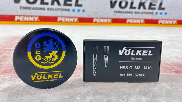Puck mit Friedensbotschaft „Drop Pucks Not Bombs“ und VÖLKEL Bohrer-Set