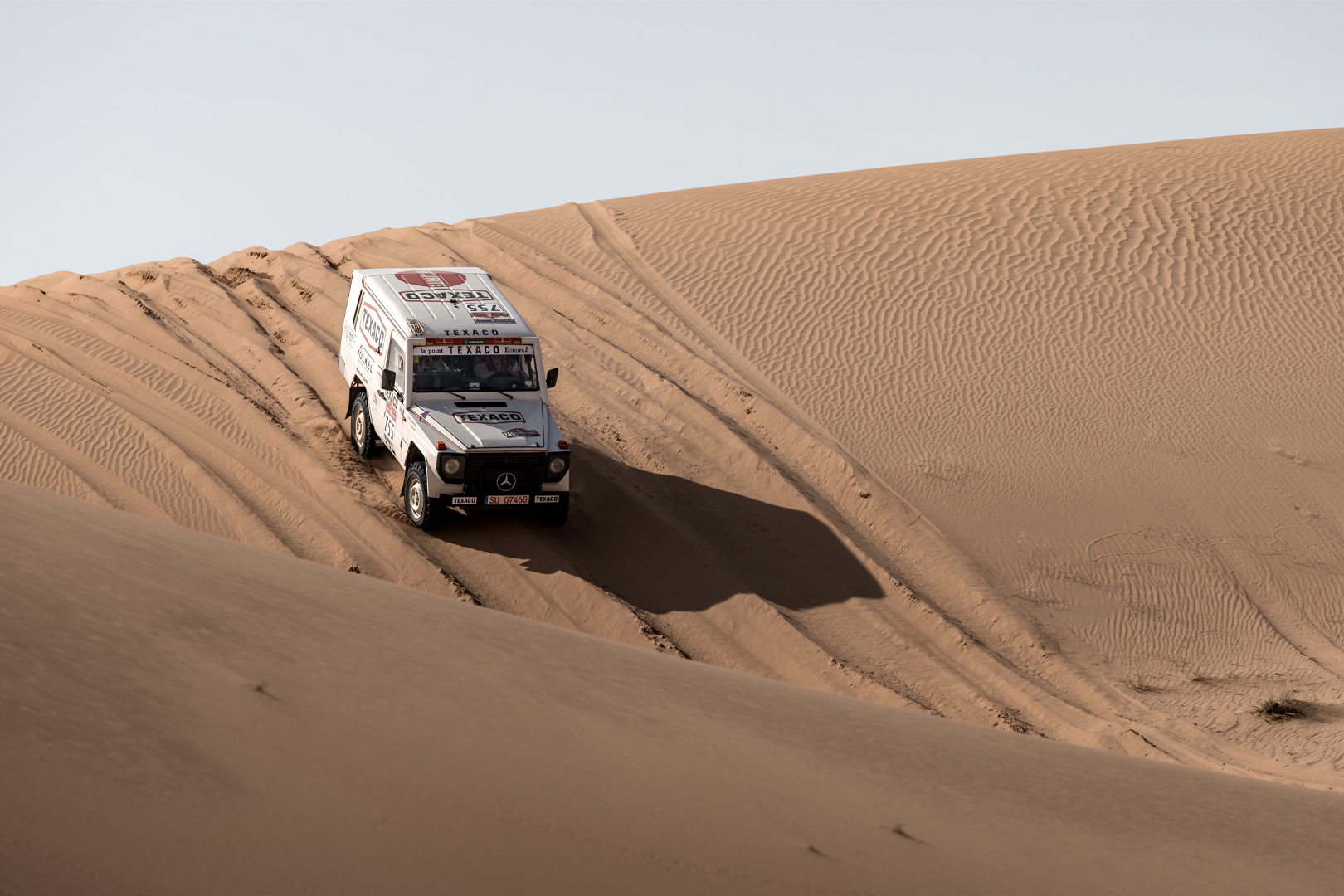 Véhicule numéro 755 avec marquage Texaco et VÖLKEL sur terrain sablonneux.