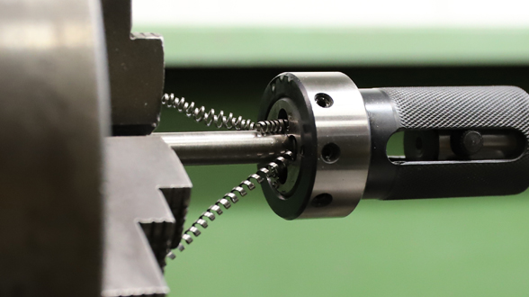 Industrielles Außengewindeschneiden auf einem rotierenden Metallzylinder.