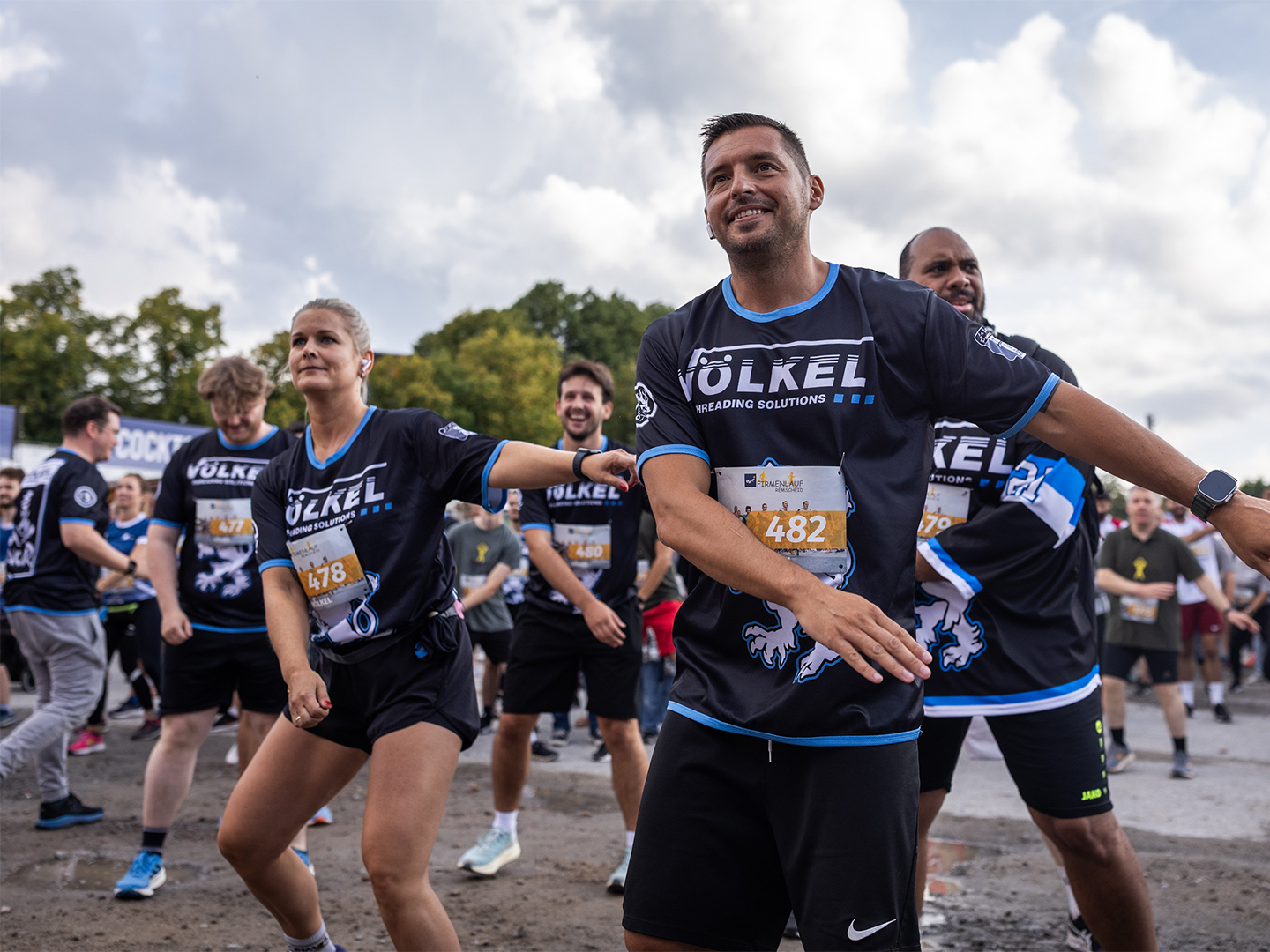 VÖLKEL-Team macht sportliche Übungen vor dem Firmenlauf. Keywords: Firmenlauf Remscheid, VÖLKEL, Team, Sportevent 2025