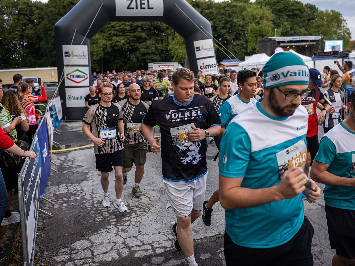 VÖLKEL-Mitarbeiter laufen durch den Startbogen des Firmenlaufs. Keywords: Firmenlauf Remscheid, VÖLKEL, Team, Sportevent 2025