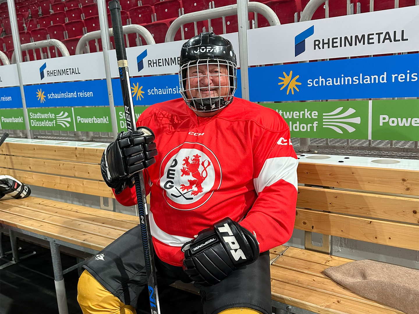 Teilnehmer des Hockey Days in rotem DEG-Trikot sitzt auf der Bank.