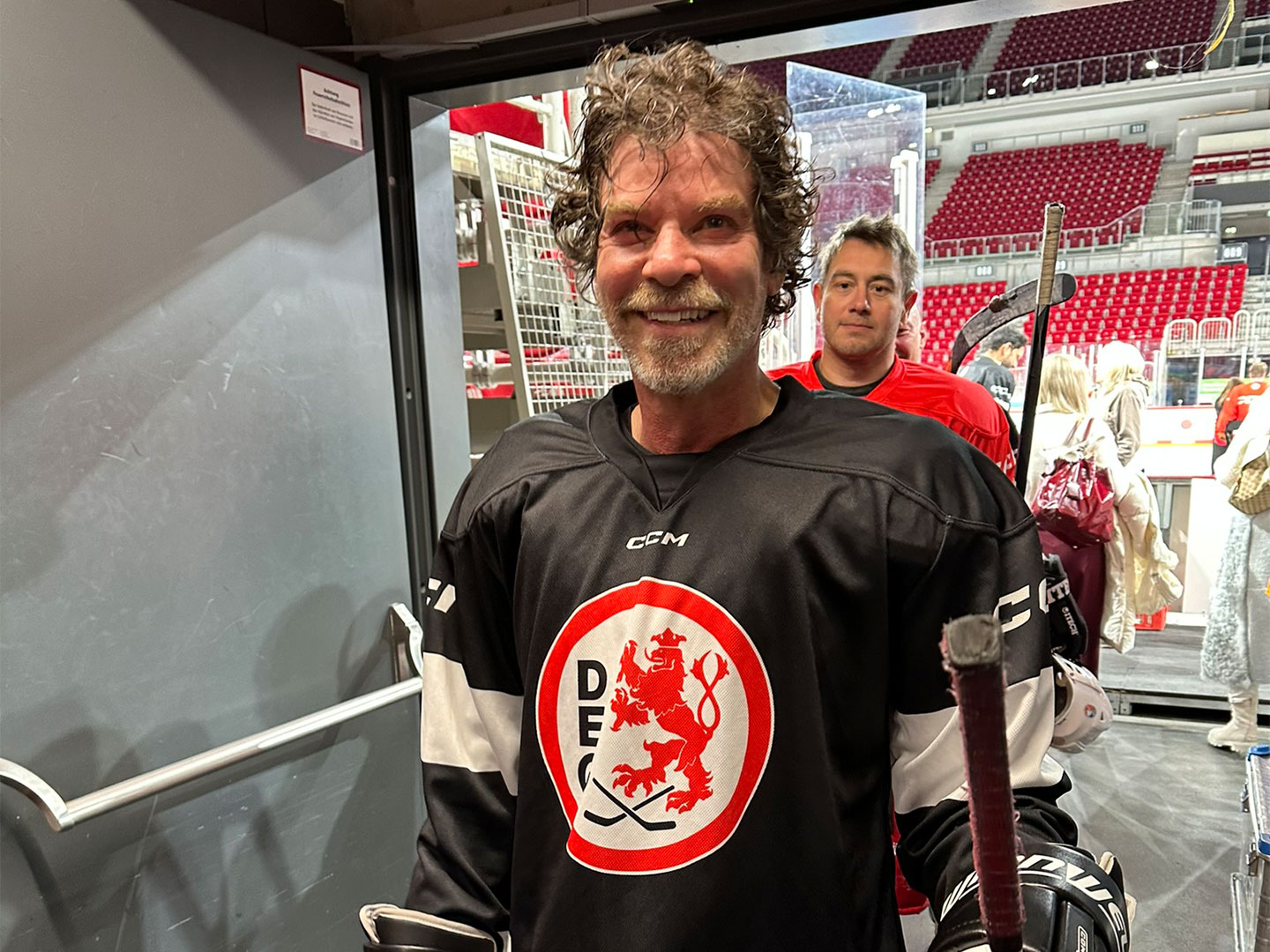 Ein Teilnehmer trägt ein schwarzes Eishockeytrikot mit einem Löwenlogo und hält einen Eishockeyschläger