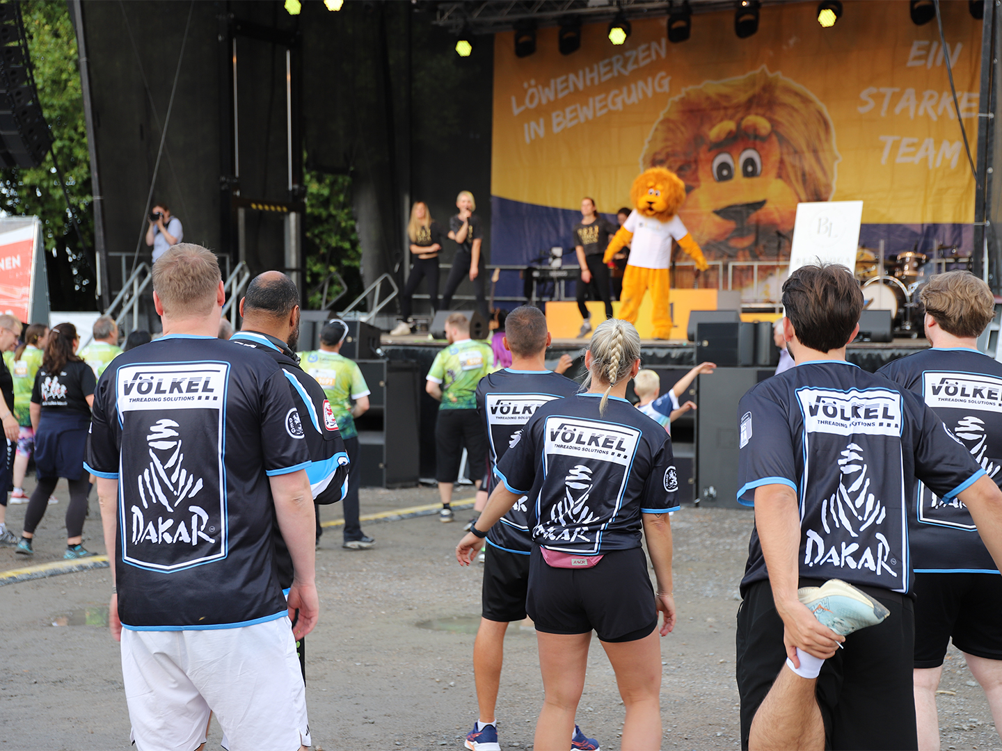VÖLKEL-Team beim Dehnen vor der Firmenlauf-Bühne. Keywords: Firmenlauf Remscheid, VÖLKEL, Team, Sportevent 2025