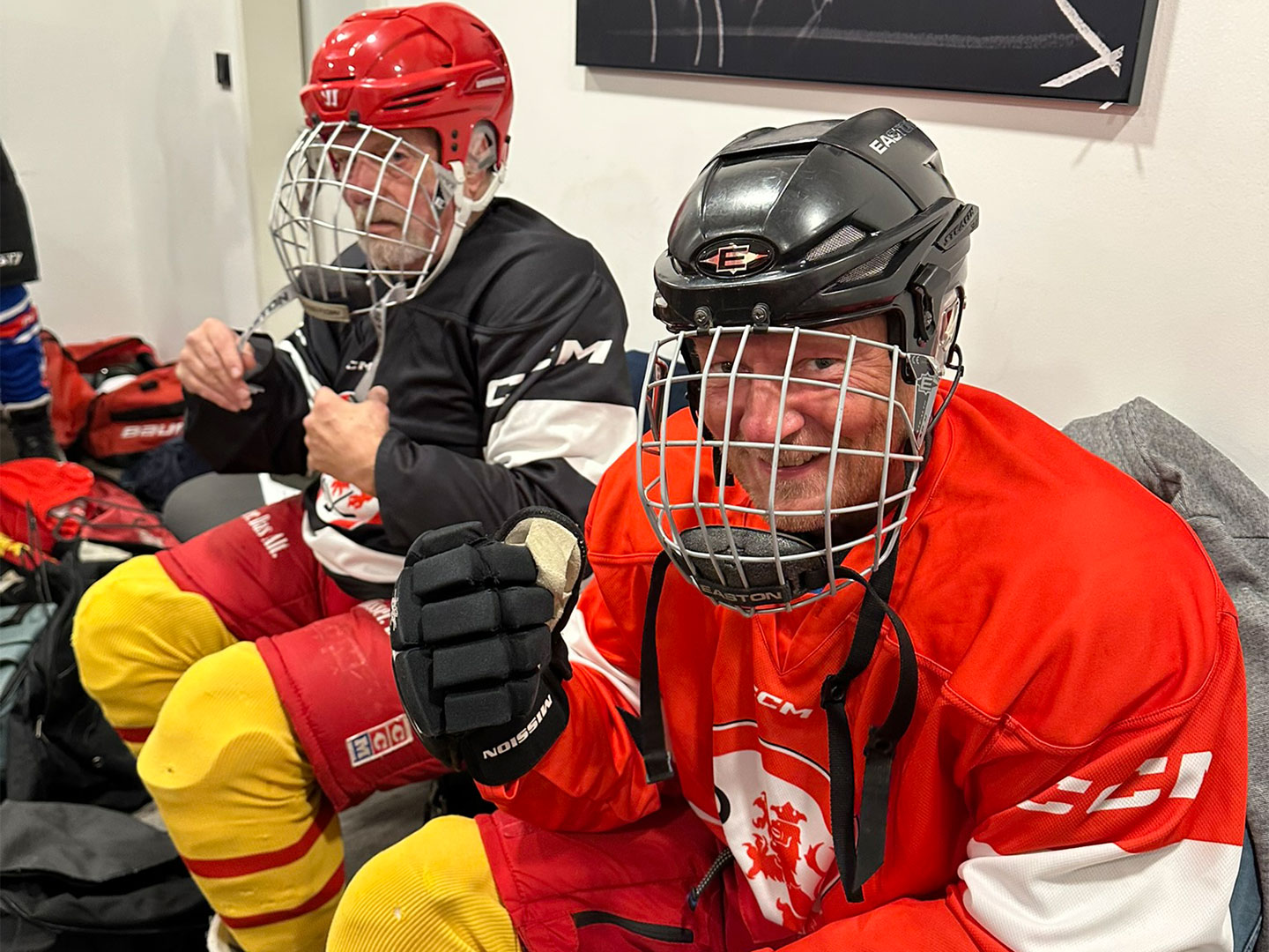 Zwei Teilnehmer des Hockey Days sitzen in einer Umkkleidekabine. Sie haben Eishockeyausrüstung an und tragen ein Helm