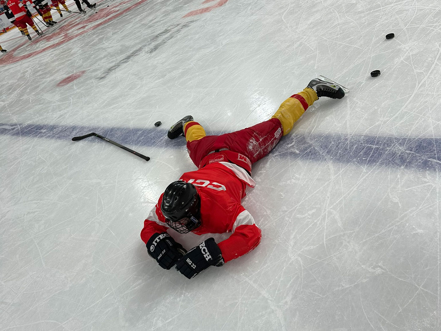 Ein Teilnehmer in roter und gelber Ausrüstung liegt auf dem Eis.