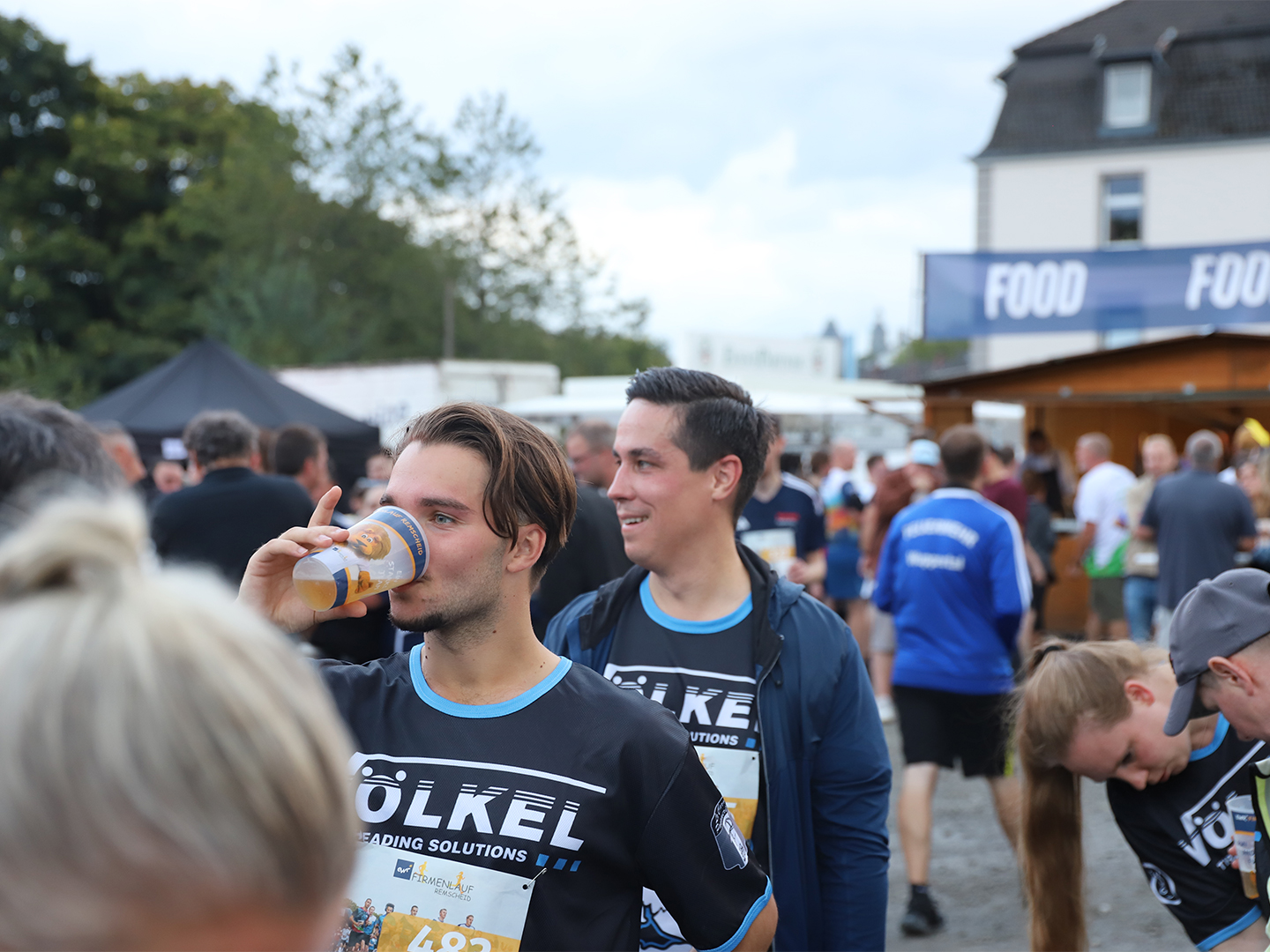 VÖLKEL-Mitarbeiter erholt sich mit Getränk nach dem Firmenlauf. Keywords: Firmenlauf Remscheid, VÖLKEL, Team, Sportevent 2025