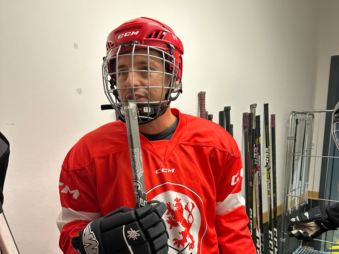 Ein Teilnehmer des Hockey Days tragt ein Rotes Trikot. Er hält ein Eishockeyschläger in der Hand.