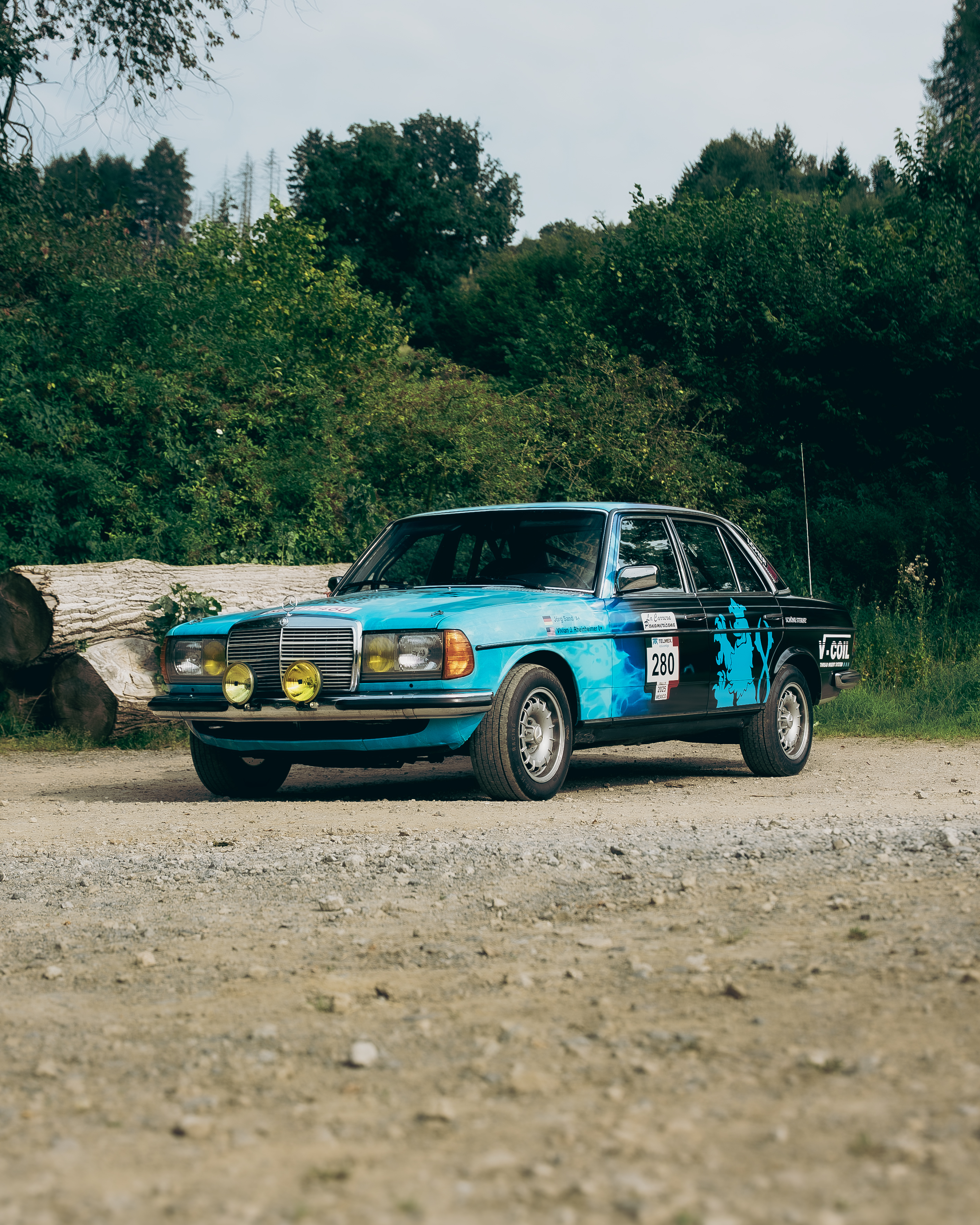 Mercedes-Benz 280E W123 Front Rallye VÖLKEL Vorderansicht des blauen Mercedes-Benz 280E W123 mit gelben Rallye-Scheinwerfern bei der Carrera Panamericana, gesponsert von VÖLKEL Threading Tools.