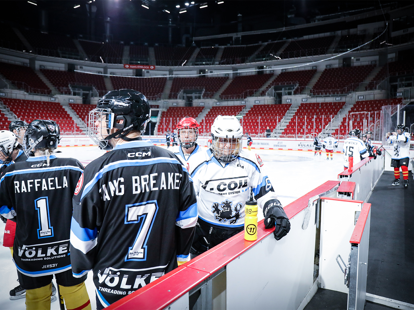 4 Teilnehmer des Hockey Days stehen an der Bande des Eisrings