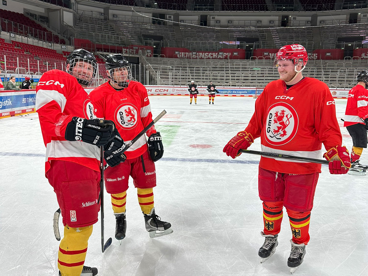 Eine Gruppe von Eishockeyspielern in roten Trikots steht auf dem Eis.