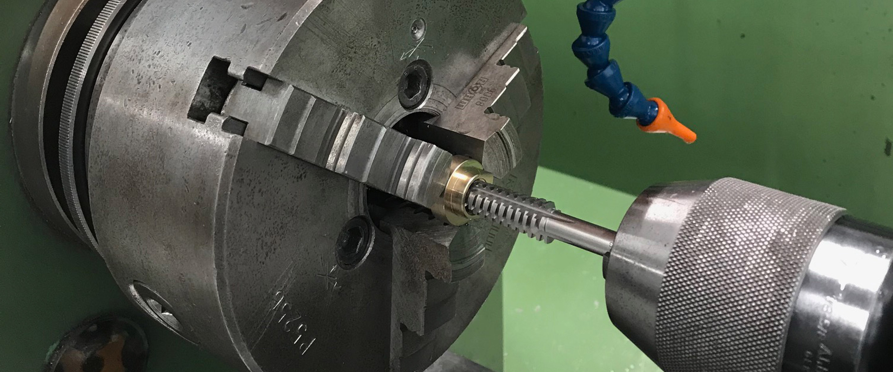 Präzises Gewindeschneiden eines Metallteils mit einem Maschinengewindebohrer in einer Drehmaschine.