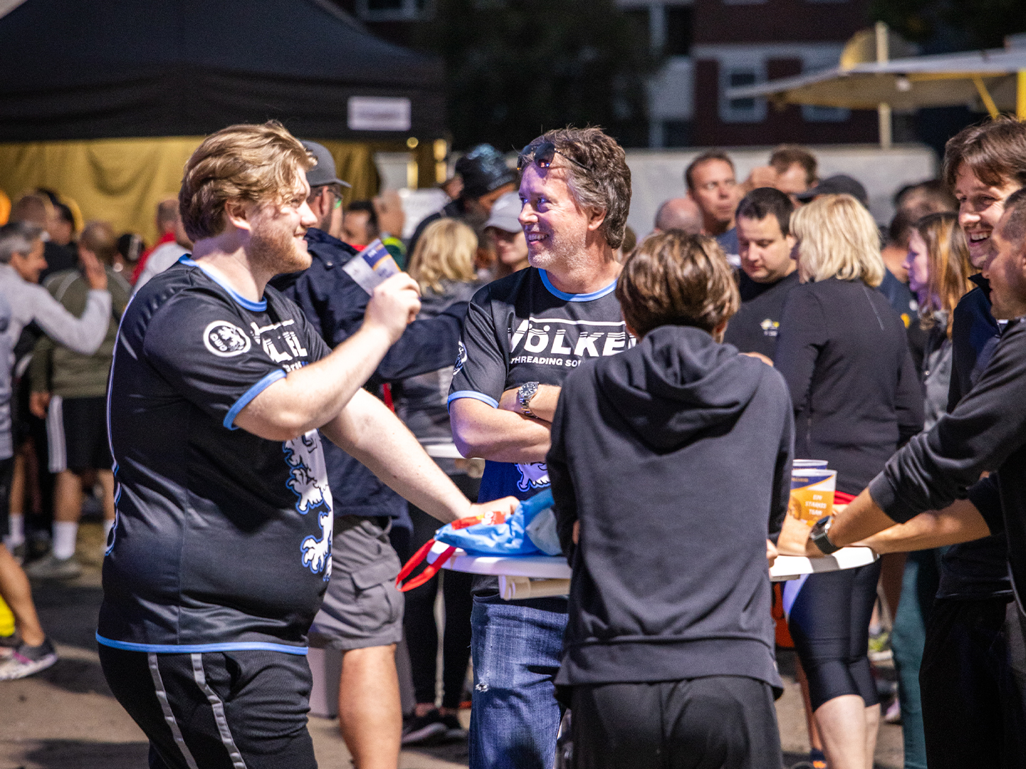 VÖLKEL-Mitarbeiter unterhalten sich am Tisch nach dem Lauf. Keywords: Firmenlauf Remscheid, VÖLKEL, Team, Sportevent 2025