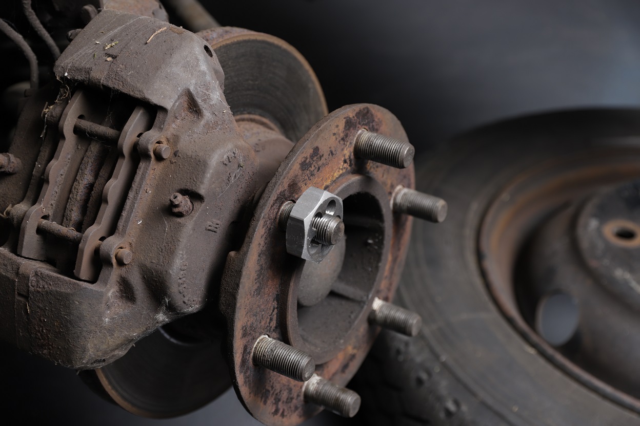 M12x1.5 wheel stud with threading die for maintenance, close-up of hub and brake disc.