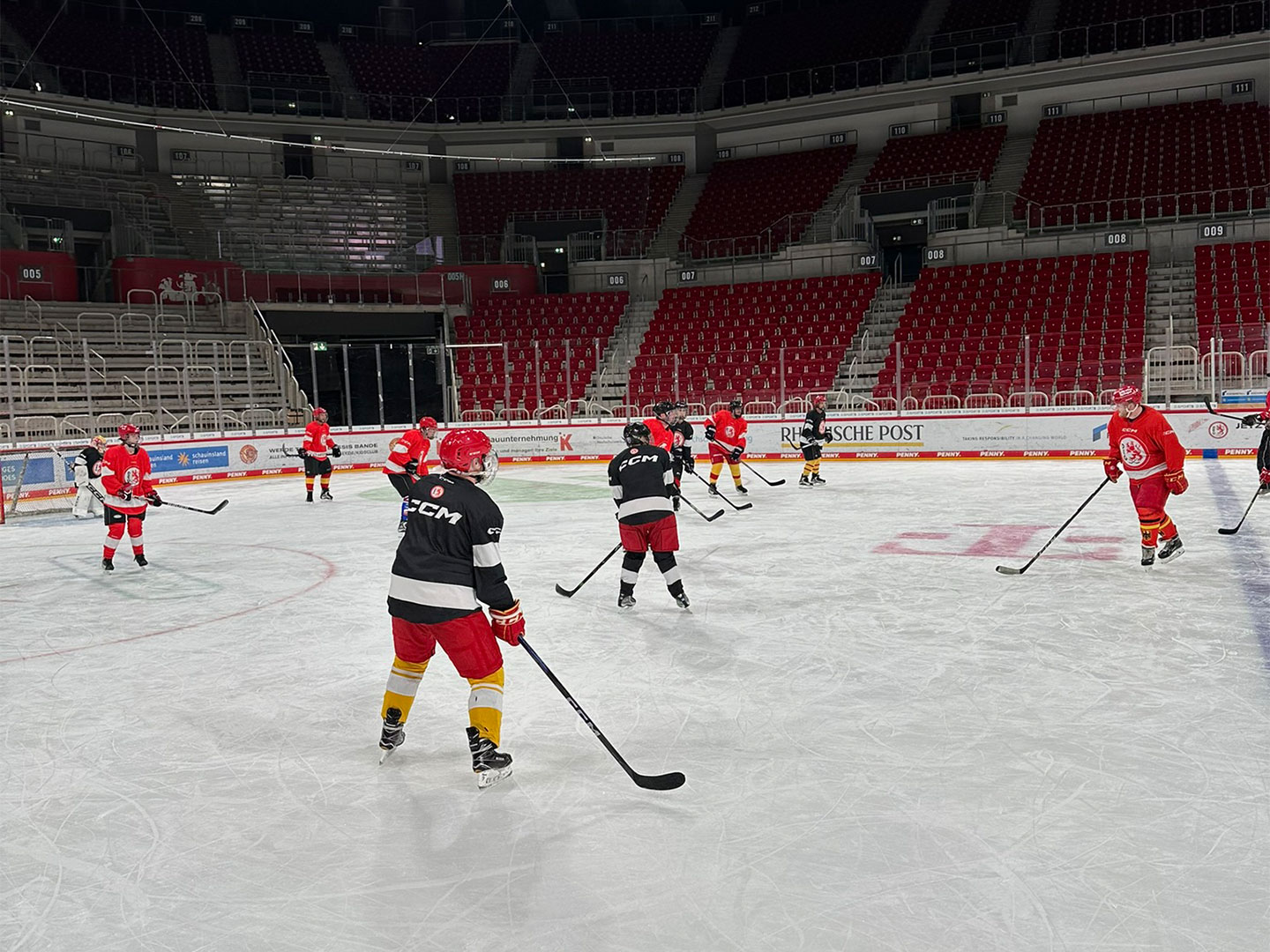 Teilnehmer des Hockey Days in roten und schwarzen Trikots spielt auf dem Eis.